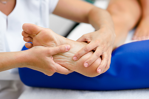 Medical massage at the foot in a physiotherapy center. Female physiotherapist inspecting her patient.